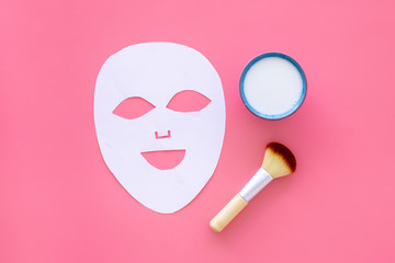 Cosmetic product for cleansing skin. Facial mask, cream and brush on pink background top view space for text
