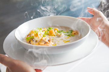 Cream mushroom soup with scallops, herbs, toast bread and dried ice mist.