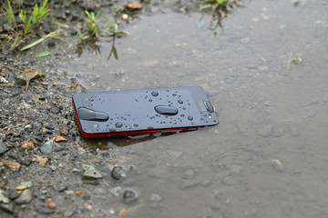 水たまりに落ちたスマートフォン