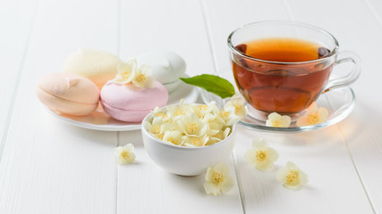 Herbal tea, a bowl of marshmallows and jasmine flowers on a table. The composition of the morning Breakfast.