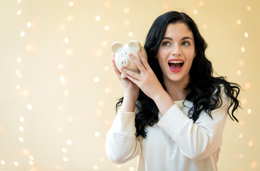 Young woman with a piggy bank on a shiny lights background