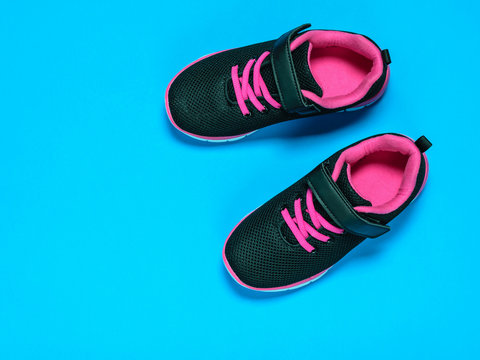 Black with red children's sneakers on a pink background.
