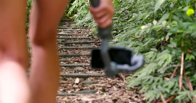 Woman taking video on cellphone with stabilizer in countryside