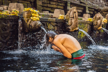 Man in holy spring water temple in bali. The temple compound consists of a petirtaan or bathing...