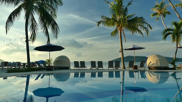 Swimming pool with umbrella and chair on sea view background