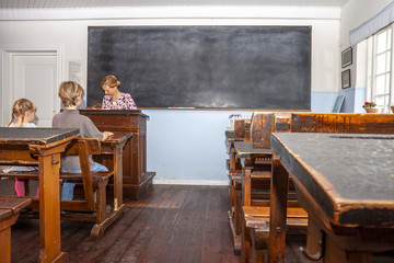 Concept of public primary school education with young boy and girl listening to the female teacher