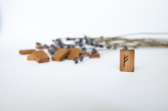 Fehu. Scandinavian runes. Wooden runes on a table on a white background.