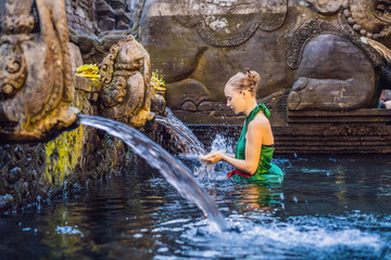 Woman in holy spring water temple in bali. The temple compound consists of a petirtaan or bathing...
