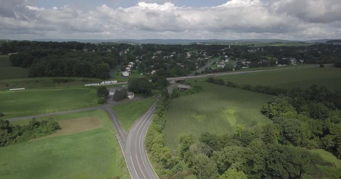An aerial shot of a road with some trucks on it. The highway is surrounded by forests and farmland. This was shot in Schnecksville, Pennsylvania