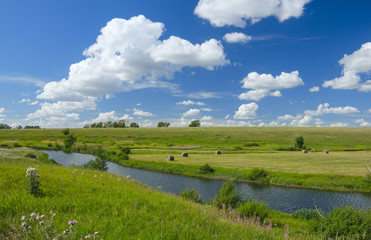 Sunny summer landscape with river,fields,green hills and beautiful clouds in blue sky.River Upa in Tula region,Russia. 