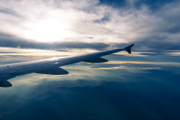 View from airplane window over clouds and mountains