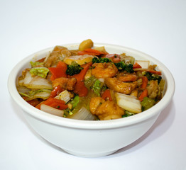 Shrimp, chicken, onion, peppers and broccoli are seasoned in a white bowl on this special and delicious porcelain dish