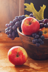 Apples and dark grape in wooden bowl.