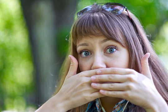 Woman close your mouth with your hands. Silence, gesture, no gossips, secret. Portrait in summer green park