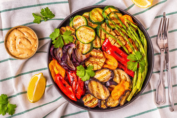 Grilled vegetables on a plate with sauce.