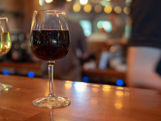 Glass of red wine sitting on counter in a winery bar counter top 
