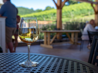 A glass of white wine sitting on patio table in a shaded outdoor dining area 