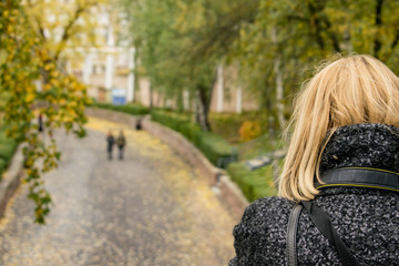 A woman is photographing standing on a bridge.