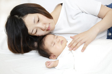 Obraz na płótnie Canvas 新生児と添い寝しながら赤ちゃんの旨に手を添える若いお母さん、親子の愛と幸せ、母性イメージ