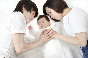 Fototapeta na wymiar 新生児と添い寝し見つめる若い父と母の両親夫婦、幸せな愛ある家族イメージ