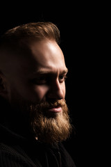 Fototapeta premium male portrait of a guy with a beard on a black background close-up