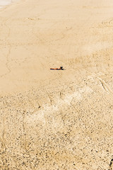 a lone person sunbathing on a large beach