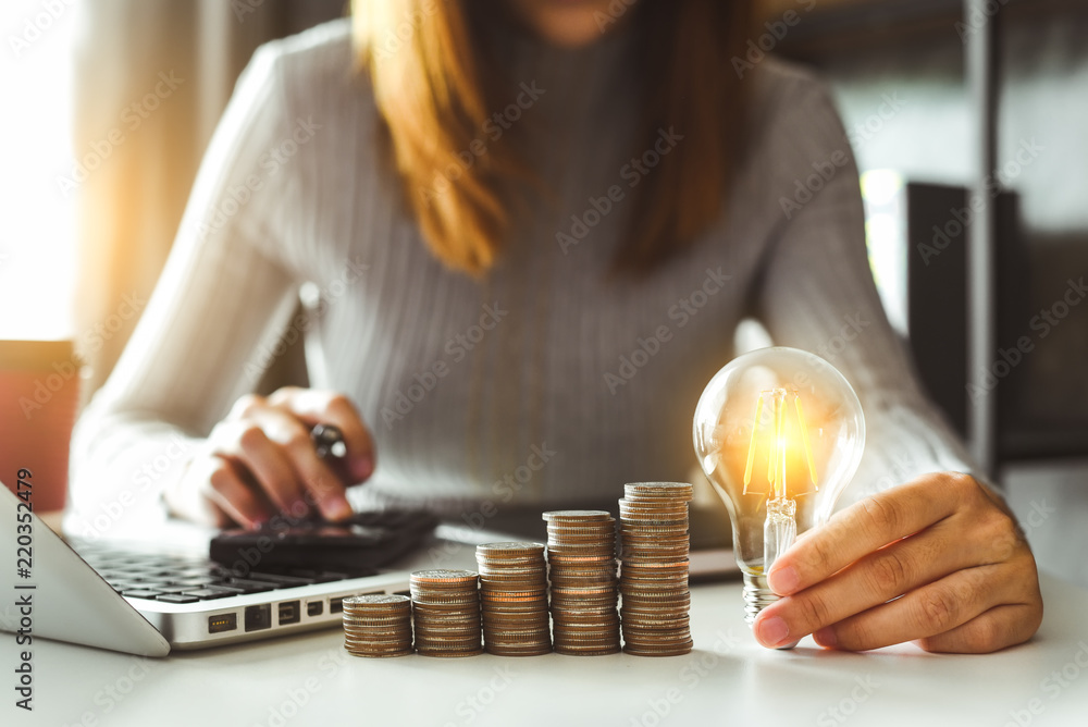 Aufkleber business man hand holding lightbulb with using smartphone and calculator to calculate and money stac
