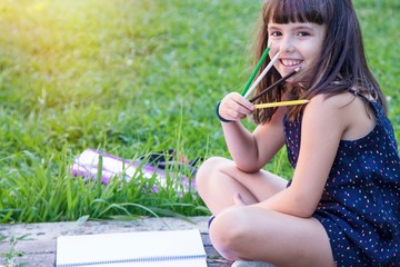 portrait of student with notebook and pencils sitting in the park