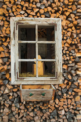 Finestra di un fienile con una pila di legna da ardere