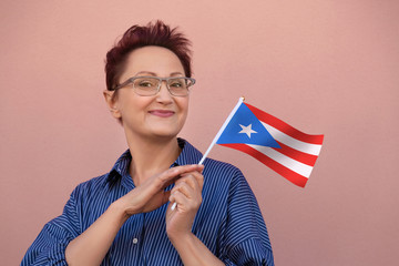 Puerto Rico flag. Woman holding Puerto Rico flag. Nice portrait of middle aged lady 40 50 years old with a national flag over pink wall background outdoors.