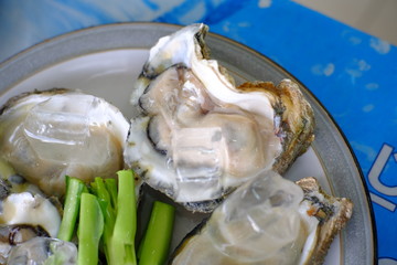 A photo of fresh opened oysters on plate with vegetable.