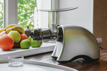 Gray horizontal juicer on table with fruit. Concept - healthy lifestyle, detox, diet, vitamins
