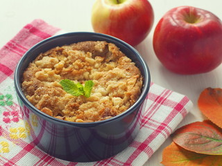 Homemade pudding decorated with autumn leaves and red apples. Portion in blue bowl. Selective focus.