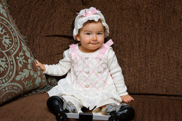 Adorable Baby Girl in Eyelet Dress and Hat Poses for the Camera She is Wearing Ponseti Method Brace Shoes to Correct a Club Foot