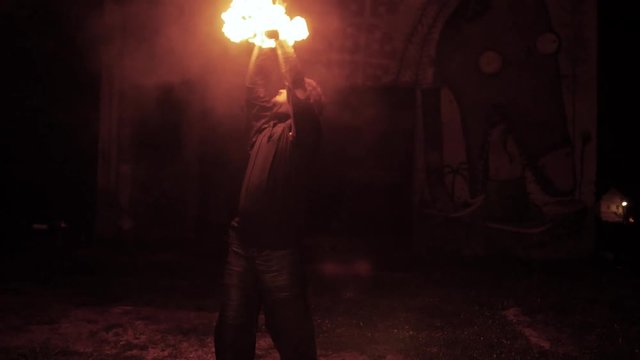 Slowmotion, A Male Fire Artist Rotate And Plays With Fire Pois In The Dark