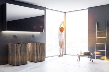 Wood double bathroom sink in black room, woman