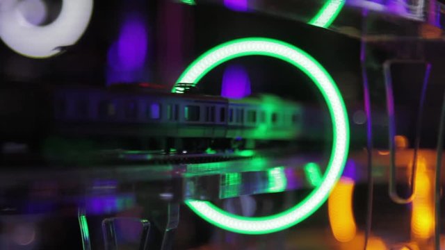 Model train passes through a ring of neon light.