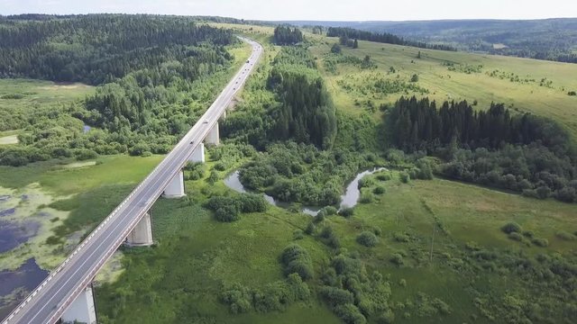 Aerial view of highway with trees and mountain. Clip. Top view of the asphalt road in forest area