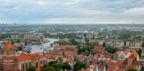 Fototapeta na wymiar City of Gdansk in Poland, aerial view over the Old Town, view from Saint Mary's Church Tower. Cityscape of Gdansk at cloudy day. Miniature effect. Selective focus