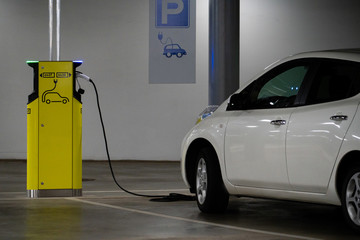 Electric car is charged at the charging station in the underground parking lot