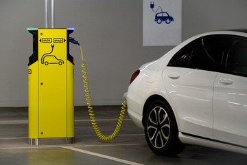 Electric car is charged at the charging station in the underground parking lot