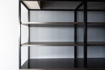 Empty Metal rod shelves with brown laminated adjustable  plank built-in with gray painted wall