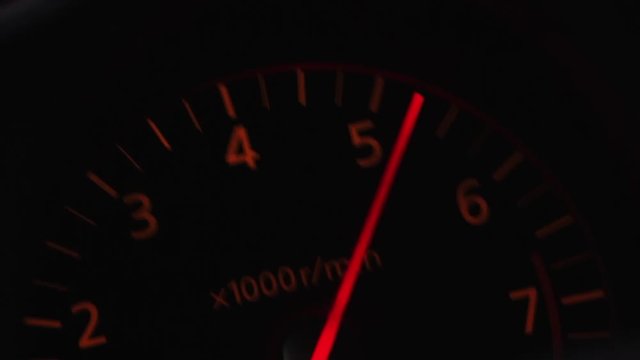 A car's tachometer hitting redline rpm.