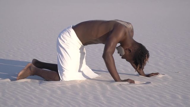 African man wanders through the desert and falls to his knees from exhaustion