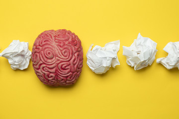 Brainstorming ideas. Brain with crumpled paper on a yellow background.