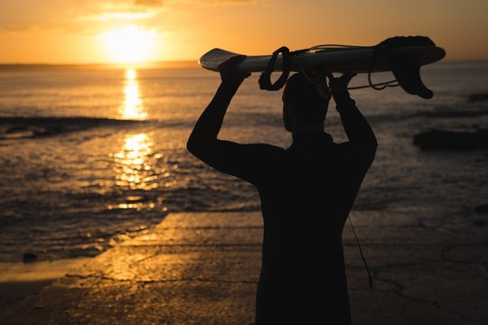Surfer carrying the surfboard on his head