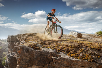 Fototapeta na wymiar Cross-Country biker on stone trail. Male cyclist rides the rock