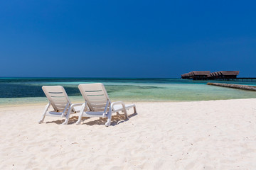 Sun lounges on an empty white Maldivian beach