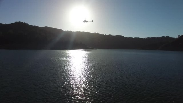 A helicopter circles above a pristine mountain lake.