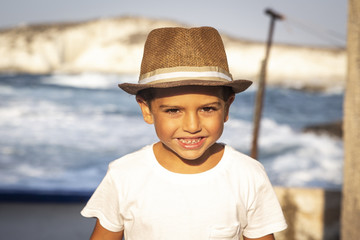 Portrait of a cute kid with hat in front of an ocean